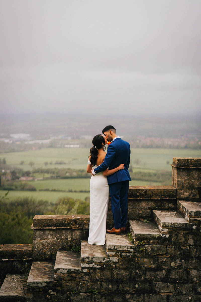 the couple kiss not he steps at hilles house whilst looking over the Gloucestershire countryside and severn valley beyond