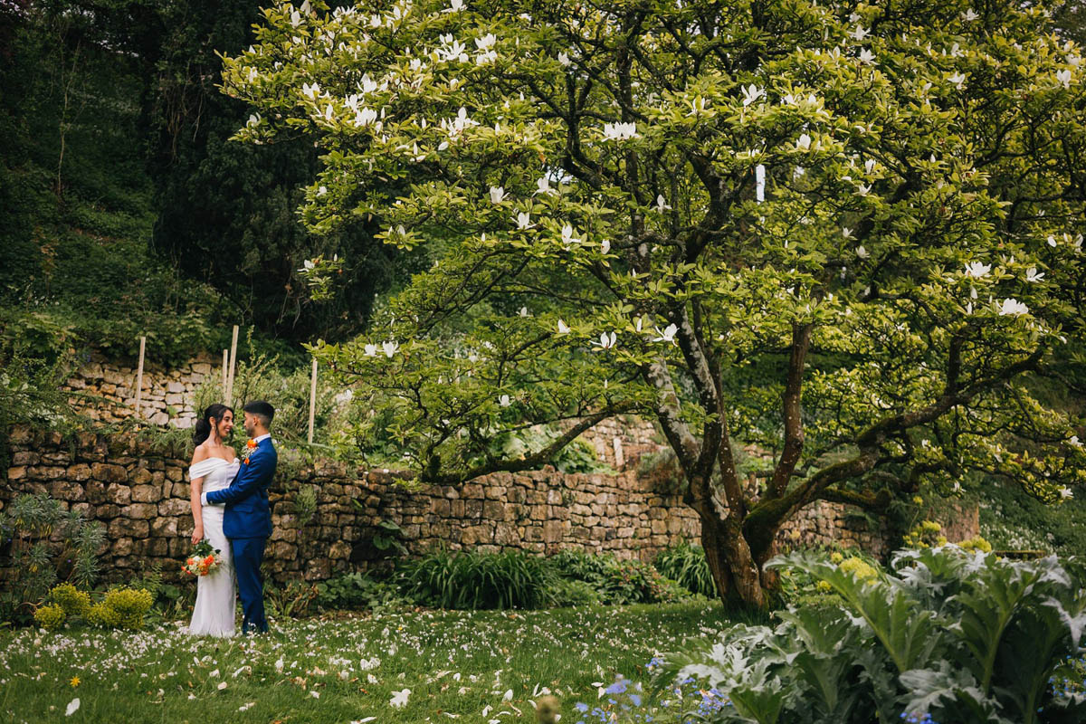 the bride and groom during their photography portraits under a blossoming tree in the gardens
