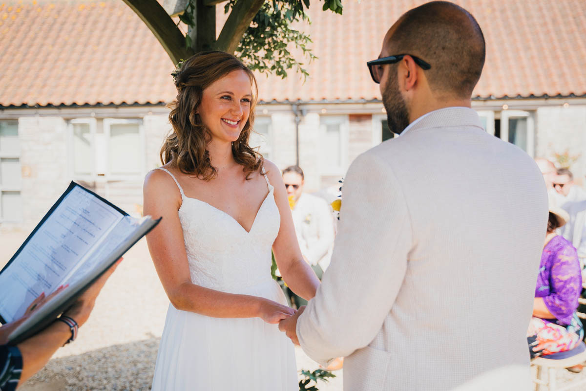 the bride smiles at her husband-to-be during the wedding ceremony