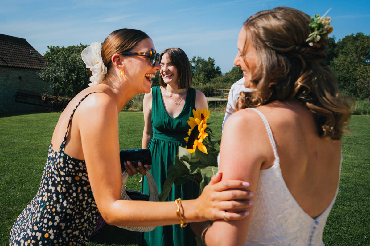 a woman laughs and touches the bride's arm