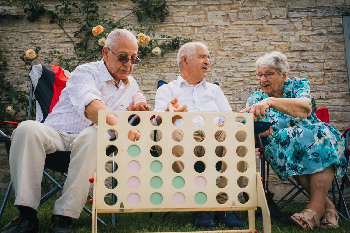 three elderly people enjoy a game of connect four