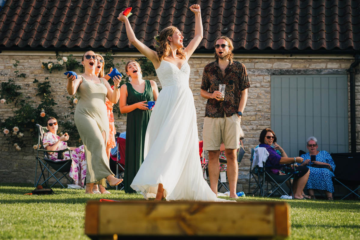 bride and her wedding guests throw bean bags and celebrate a win