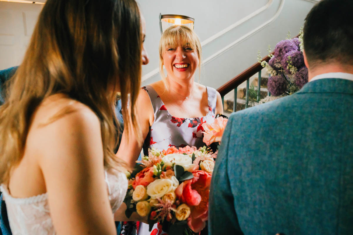 a bridesmaid smiles at the newly-weds after their intimate wedding ceremony