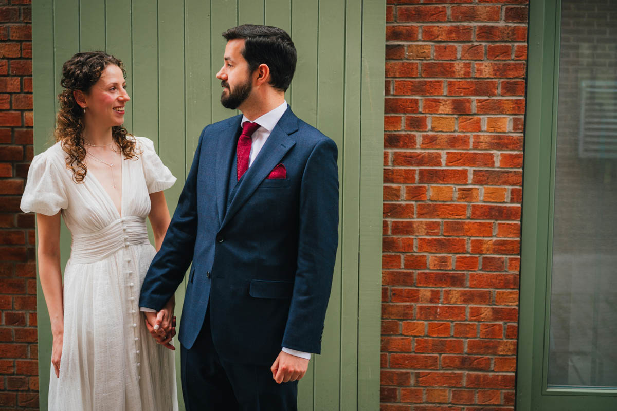 the bride and groom hold hands and look at one another