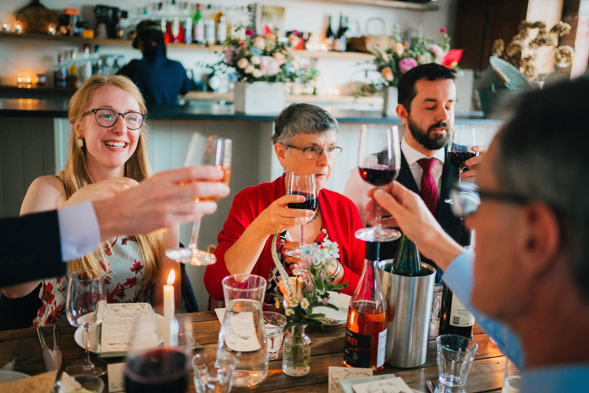 wedding guests clink wine glasses as they toast the newly-weds