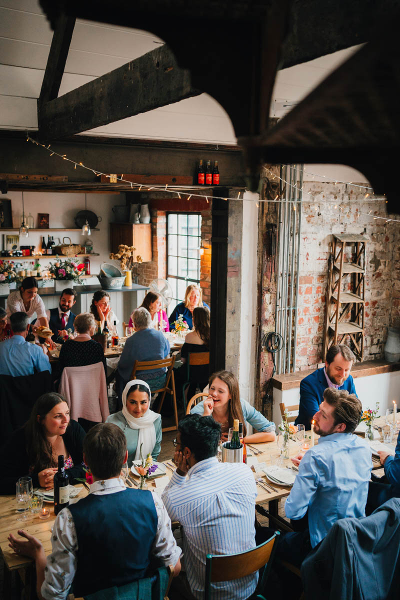 Wide-angle portrait of wedding guests seated to eat at the Forge, Bristol