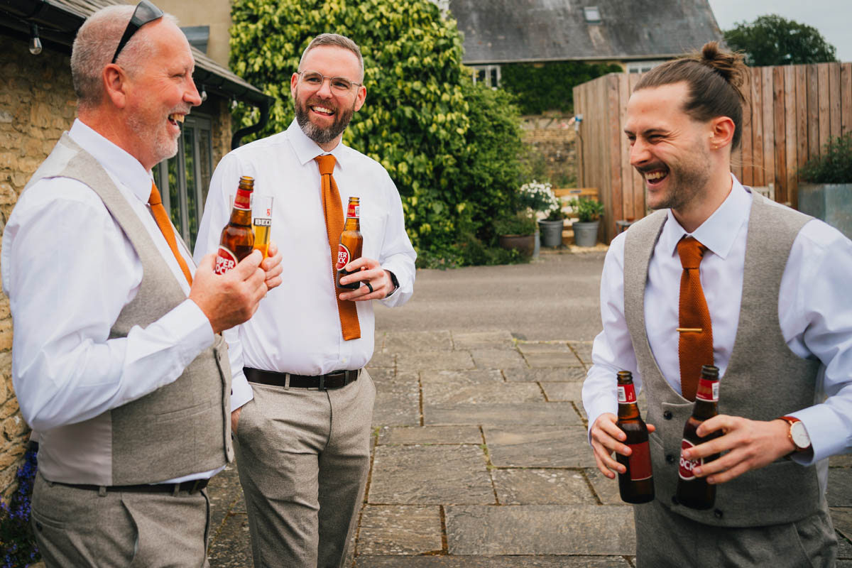 the groom and his groomsmen share a beer before the wedding