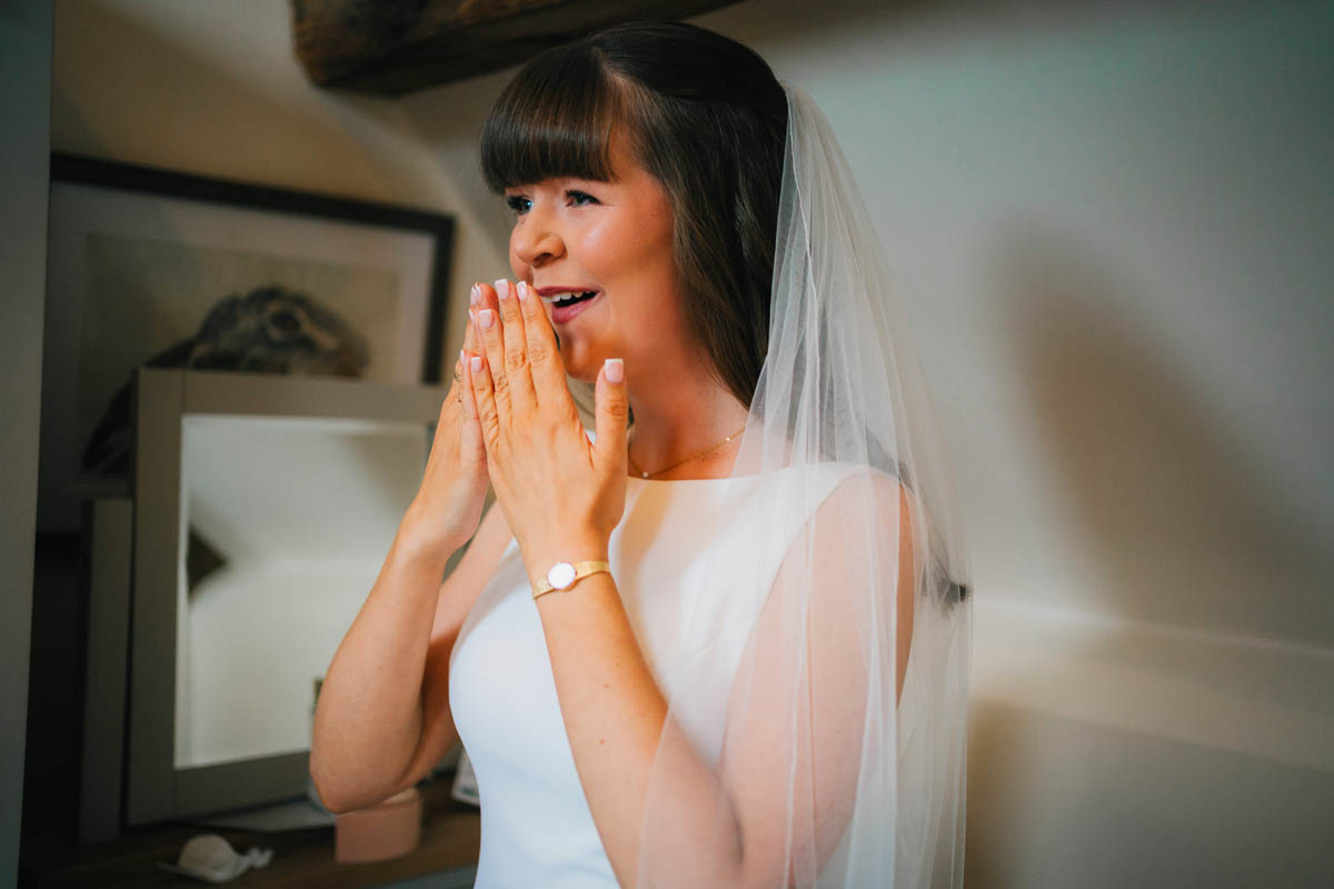 the bride gets emotional as she sees herself in the mirror for the first time in her wedding dress