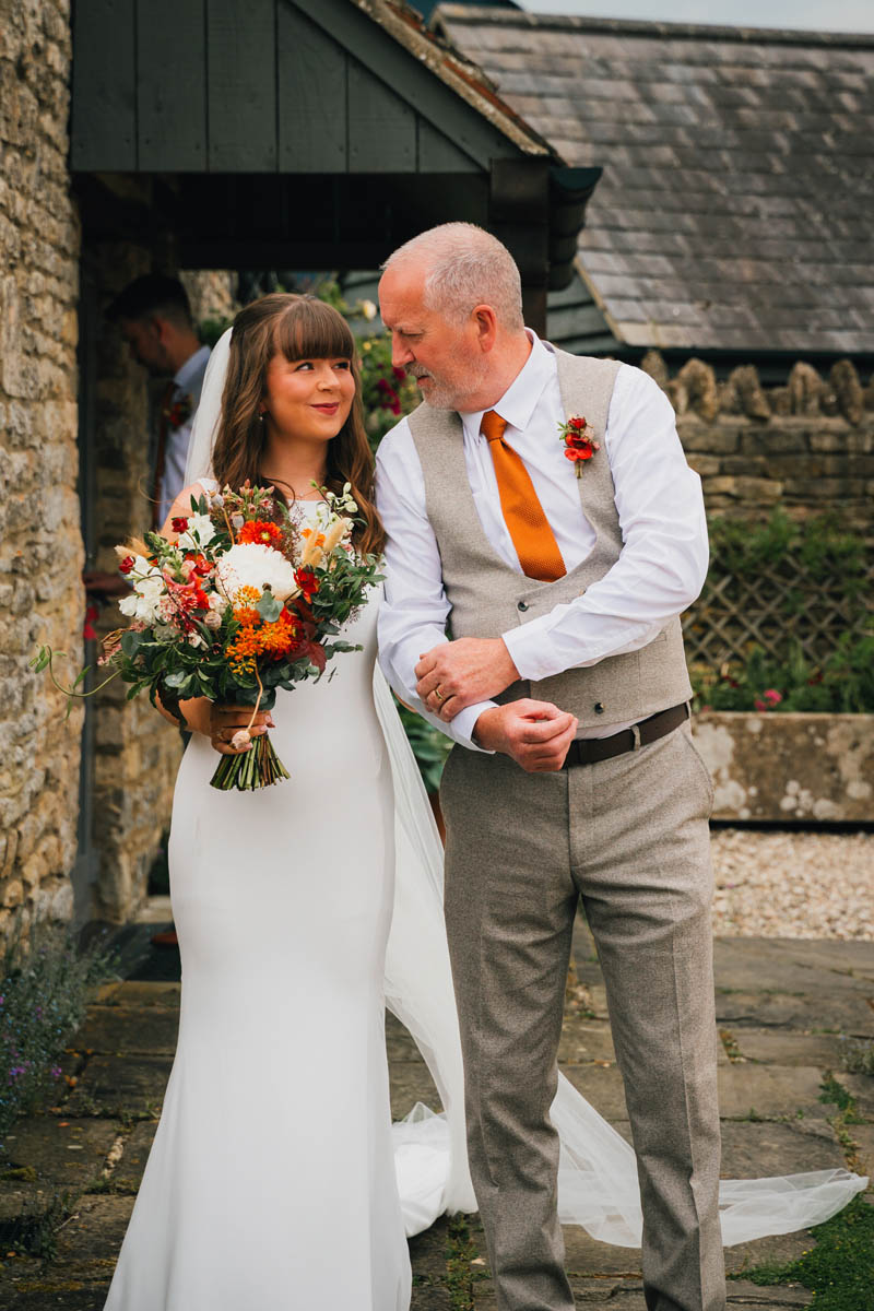 the bride smiles at her dad as he is about to walk her down the aisle