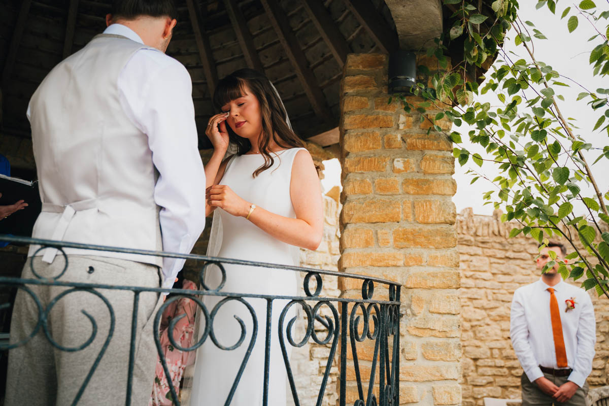 the bride wipes away a tear during the wedding ceremony