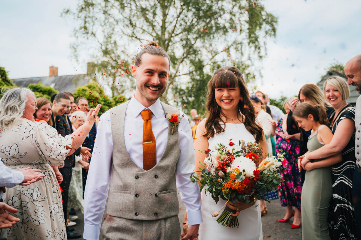 guests throw confetti over the newly-weds