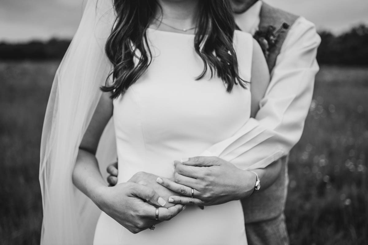 black and white close-up of the bride and groom holding hands