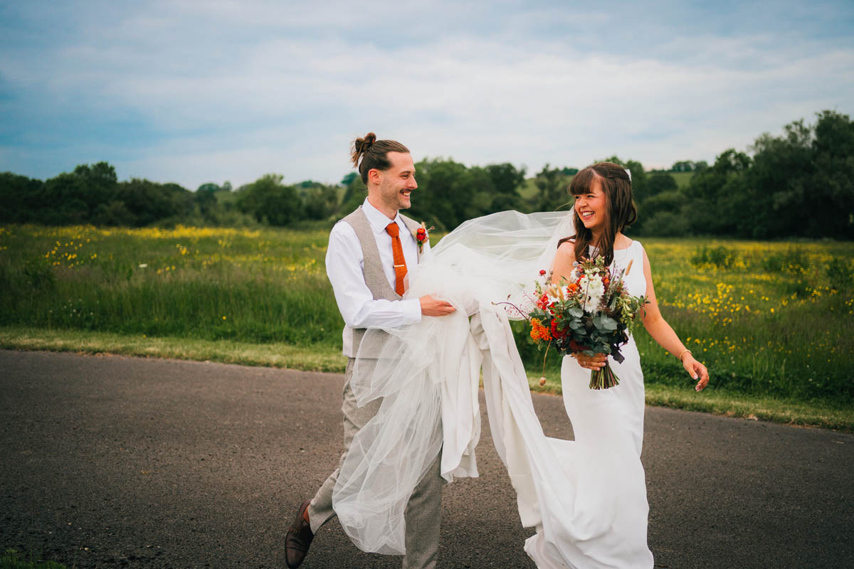 the groom holds the bride's veil and train