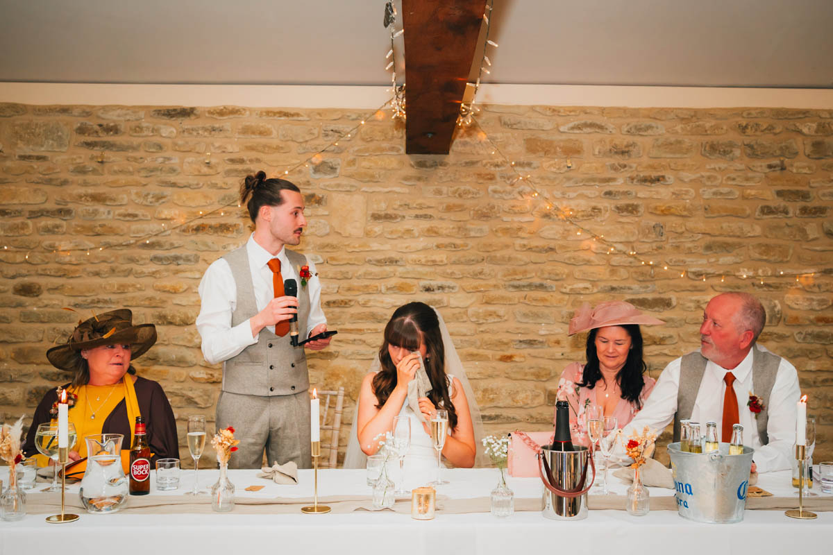 the bride wipes away a tear during the groom's speech