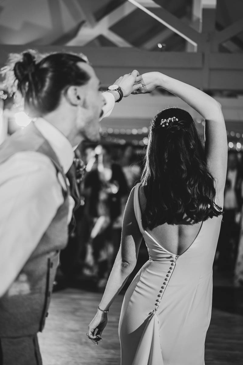 the groom swings his bride around on the dance floor