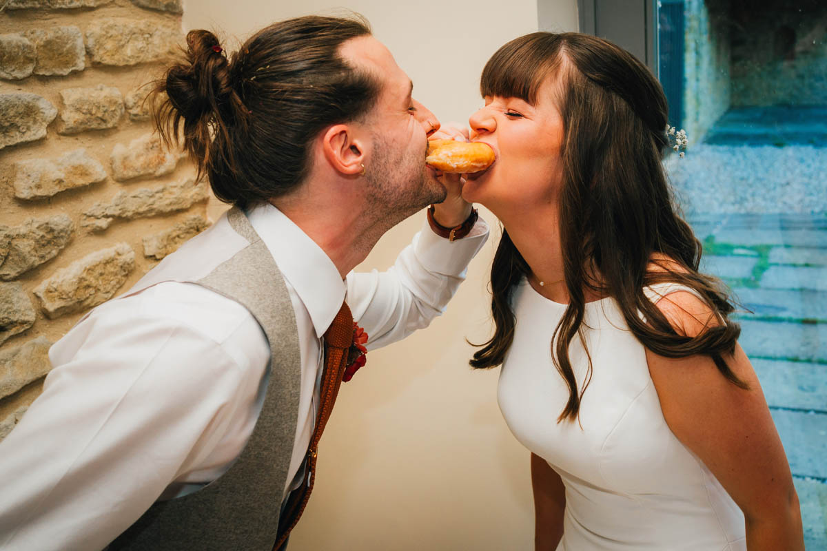 the bride and groom share a donut