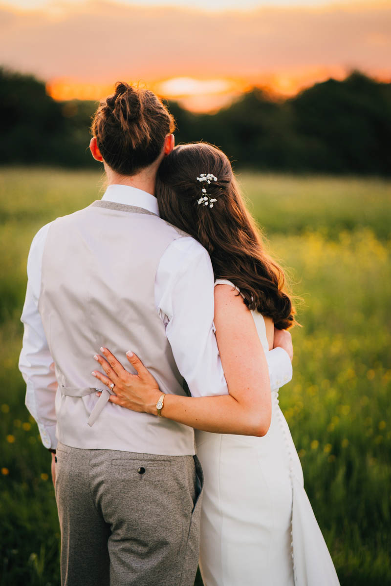 the bride hugs her new husband at sunset