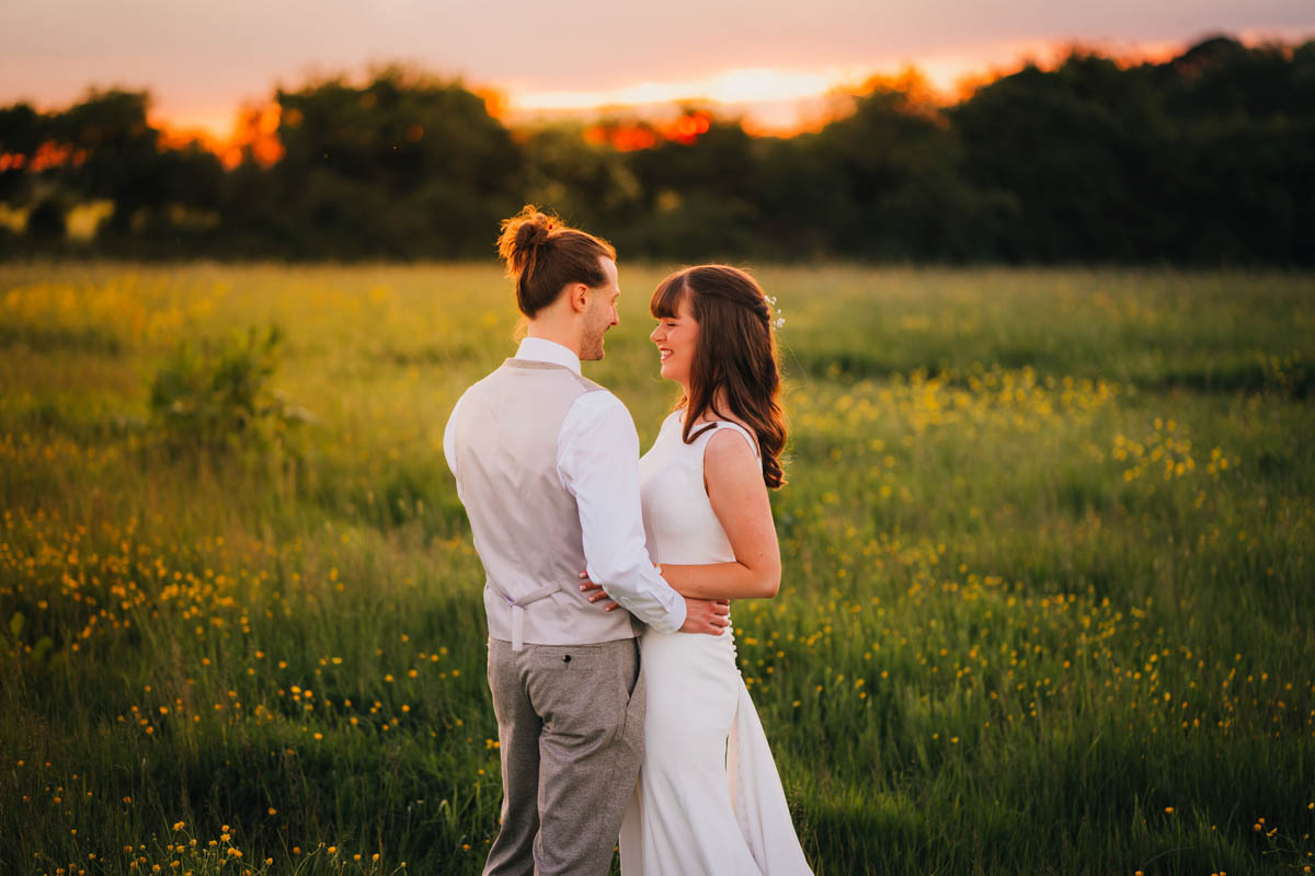 the bride and groom in a field of buttercups at sunset