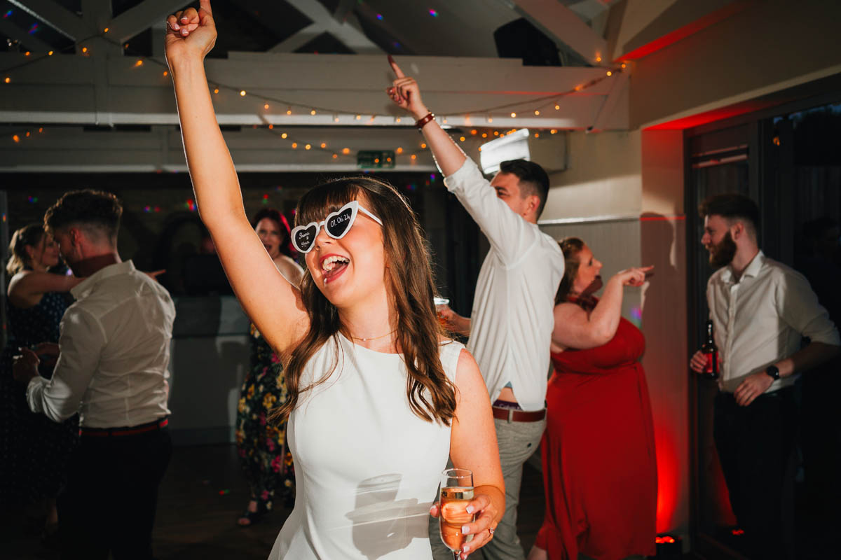 the bride throws her arms up in the air as she dances