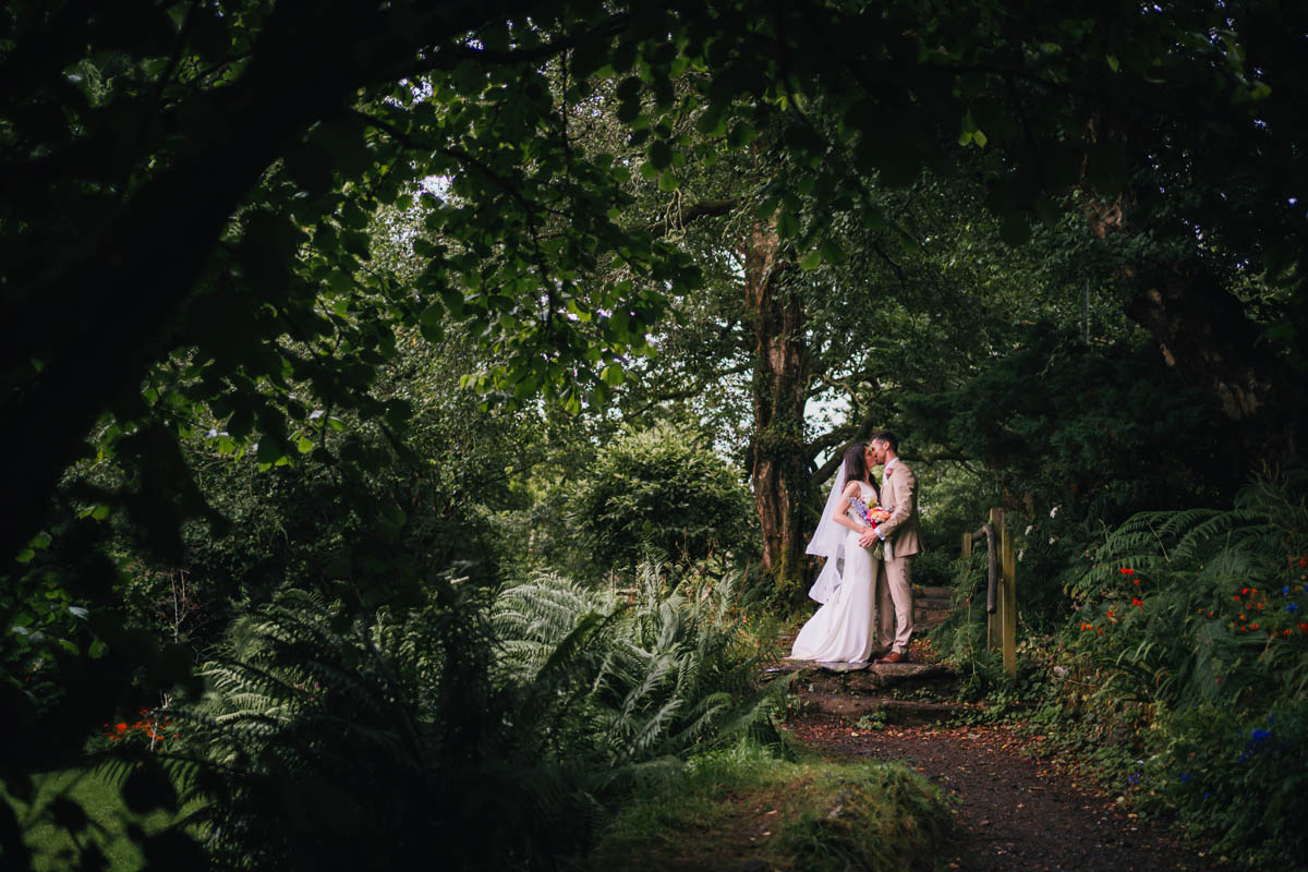 A landscape photograph of bride and groom amongst woodland and greenery