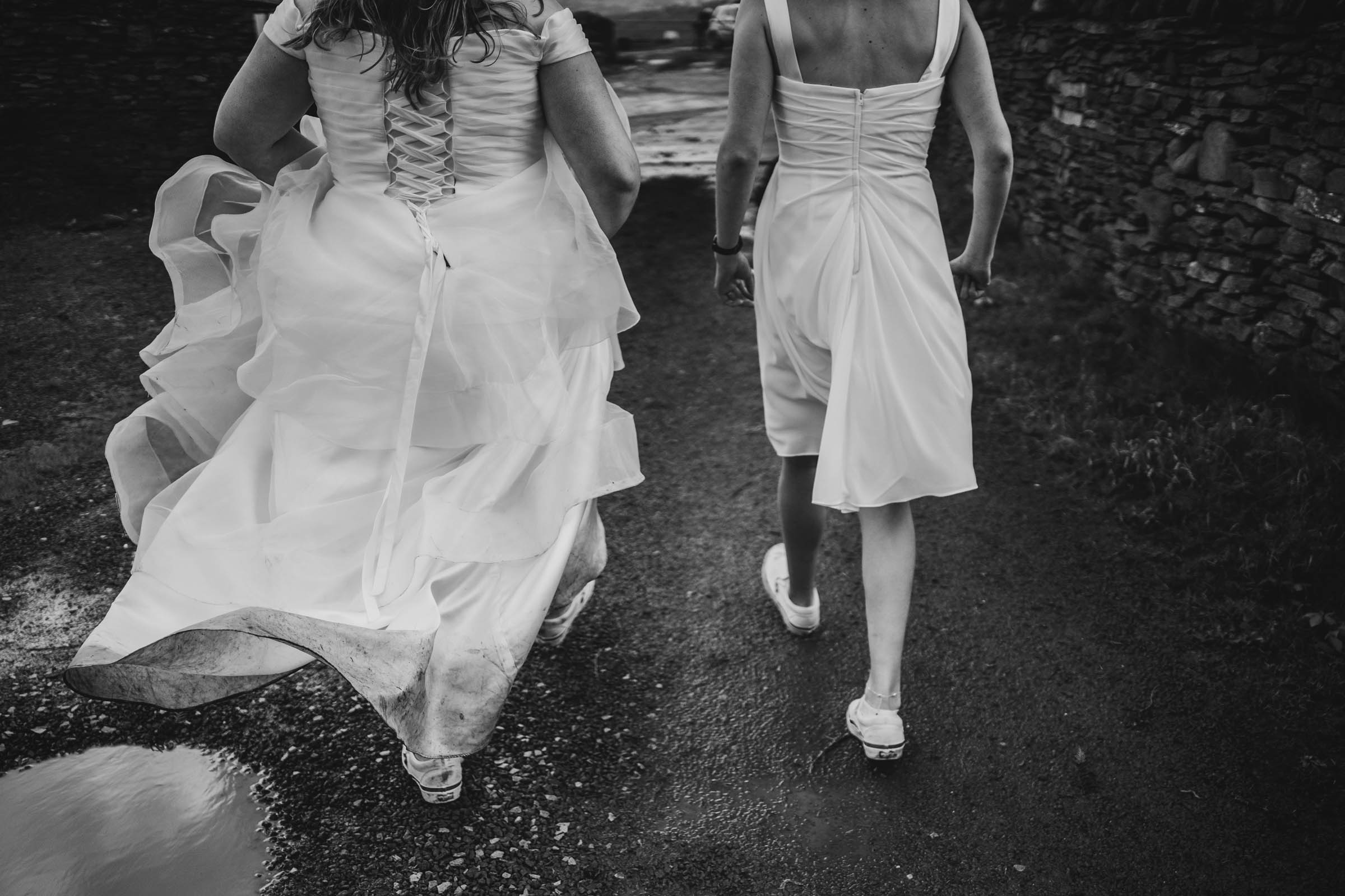 two brides run through the mud on their wedding day holding hands