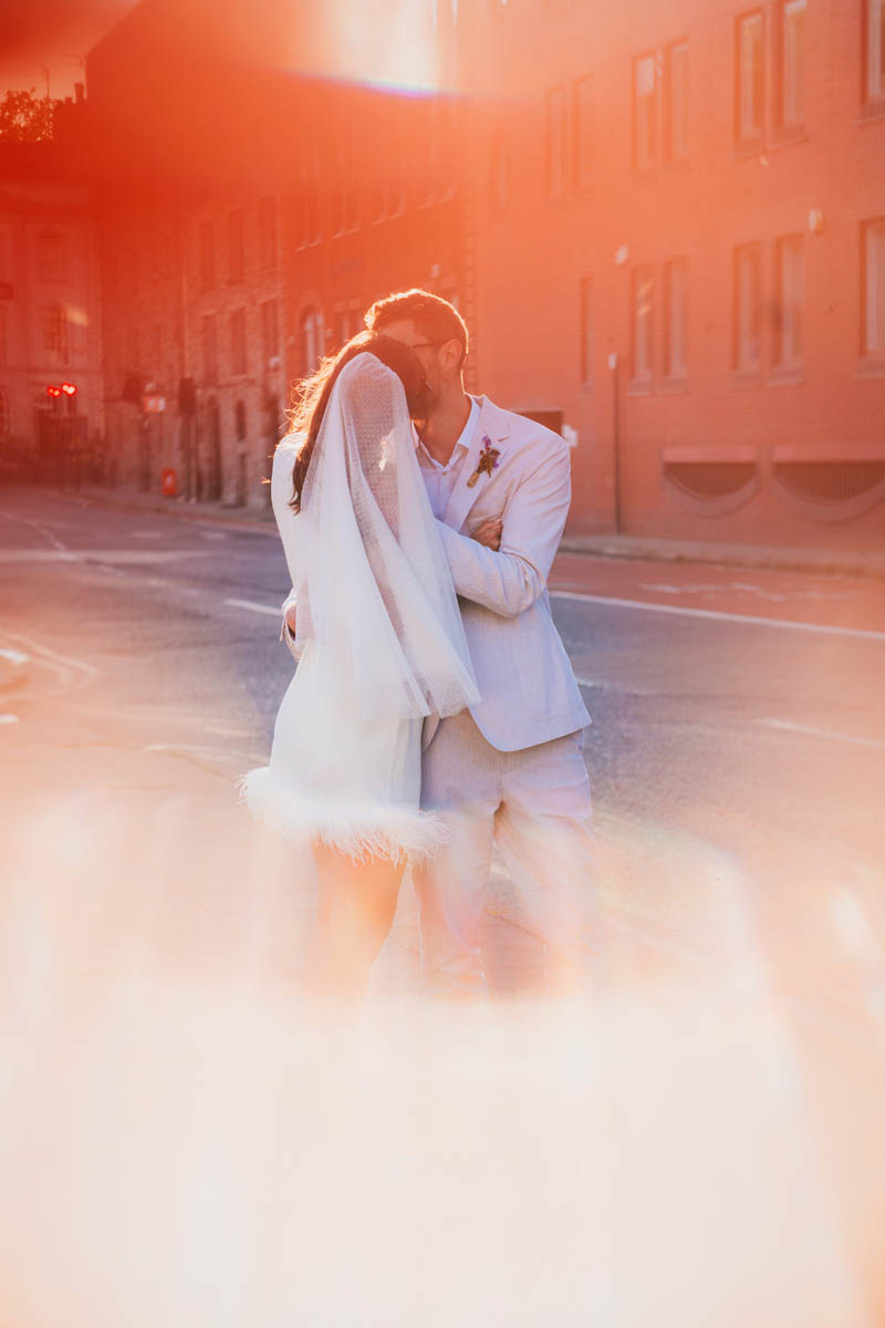 bridal portrait of the bride and her groom kissing through sun flare