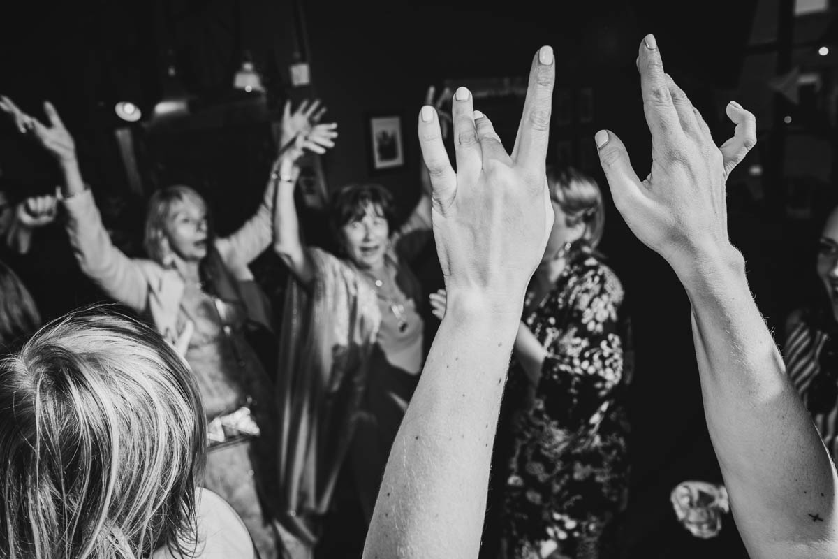 black and white close up of arms in the air on the dance floor