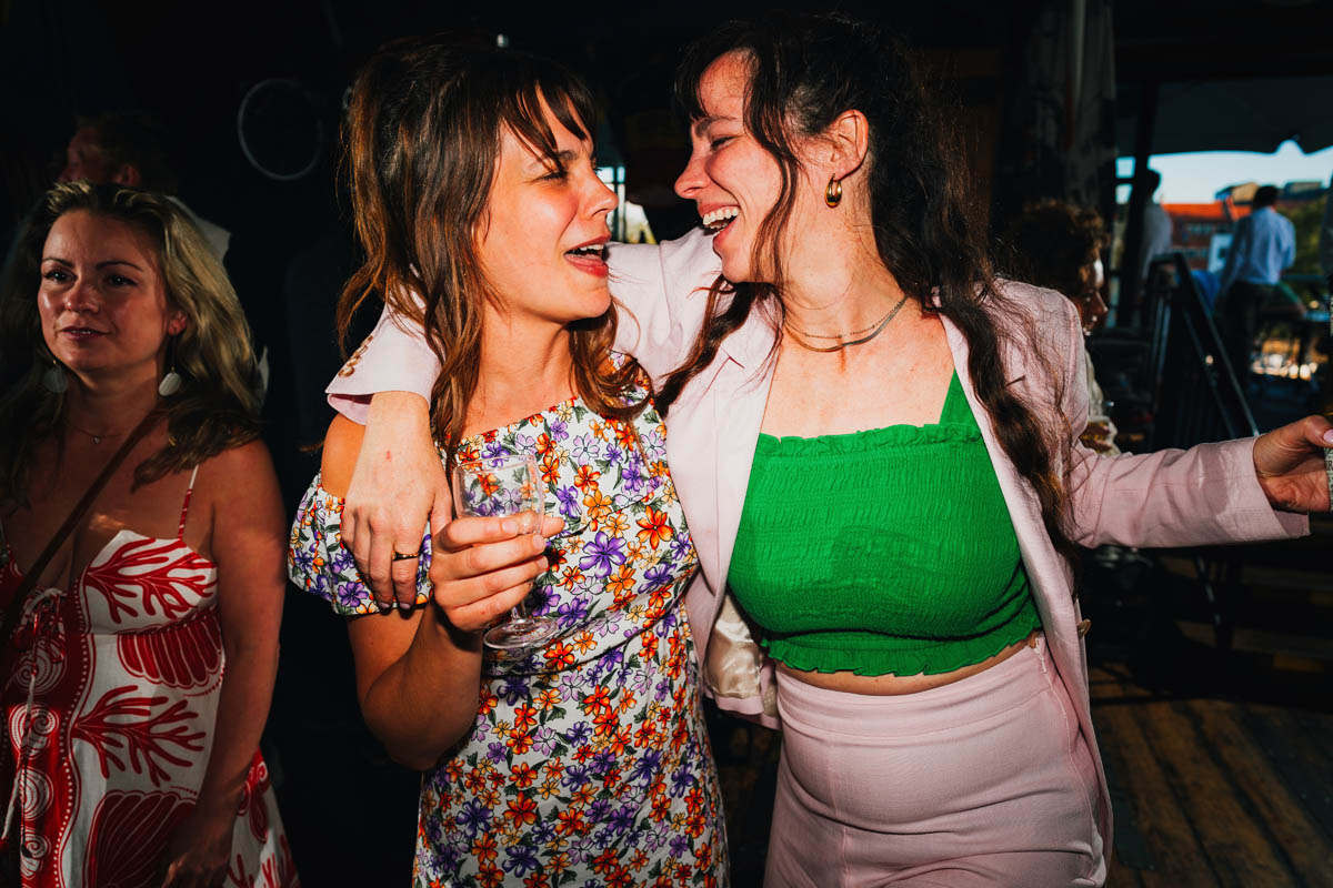 wedding guests smile and dance with each other on the dance floor