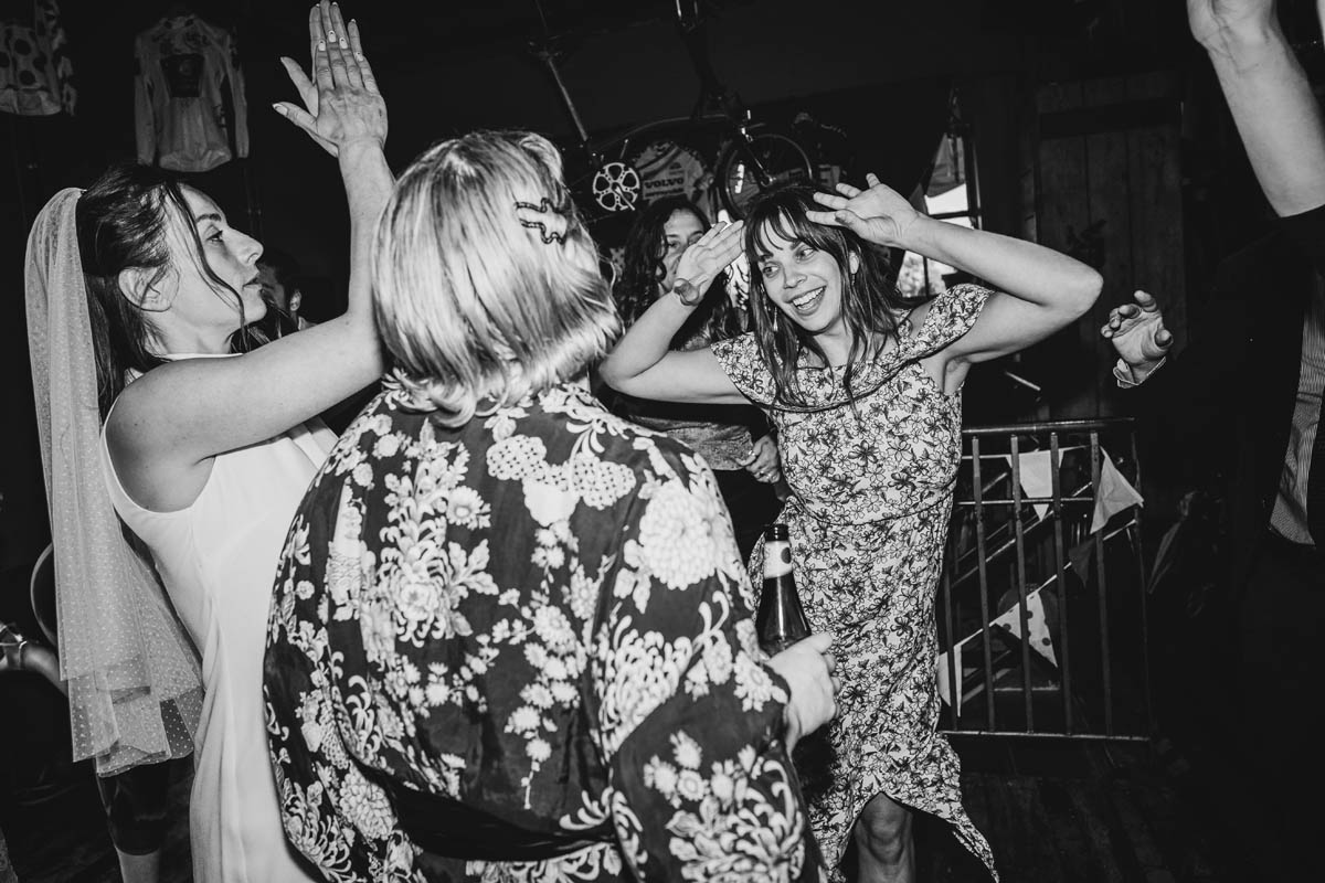 a bride dances with her bridesmaids, in black and white