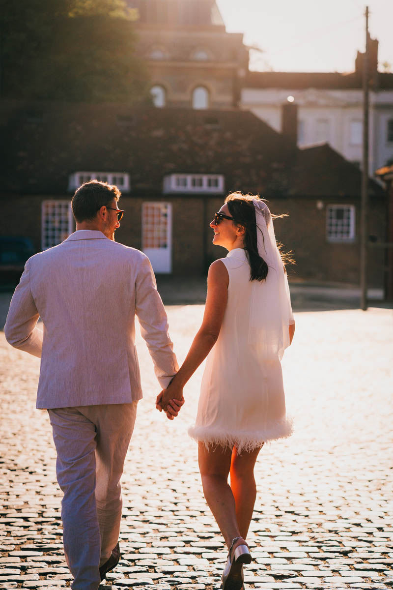 a bride and groom take a walk on their wedding day in front of the Mud dock cafe