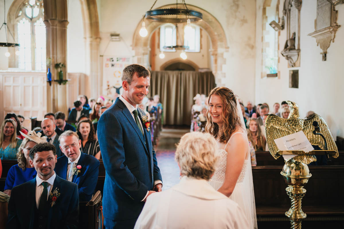 a church wedding ceremony with a bride and groom being delivered by a small female vicar