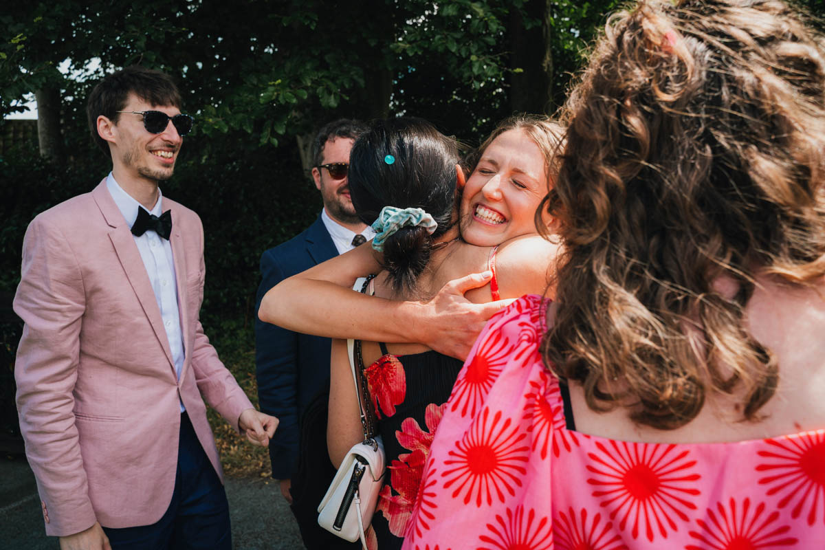 the bride hugs wedding guests with a large smile on her face