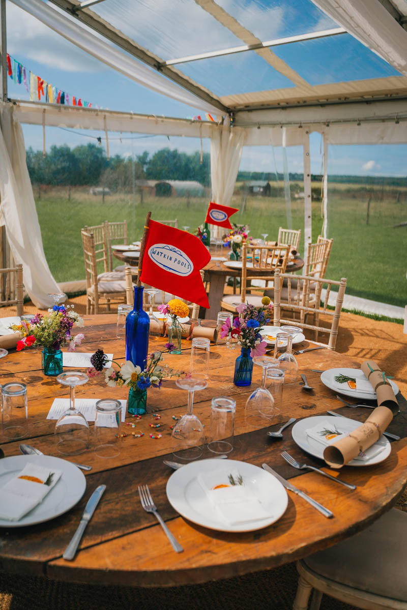 table decorations with crackers, flags in blue bottles and an assortment of colourful flowers