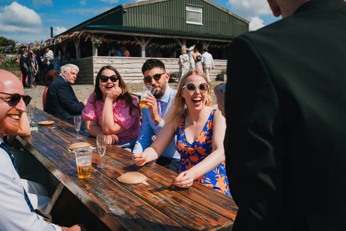 wedding guests drink and laugh at a magician performing