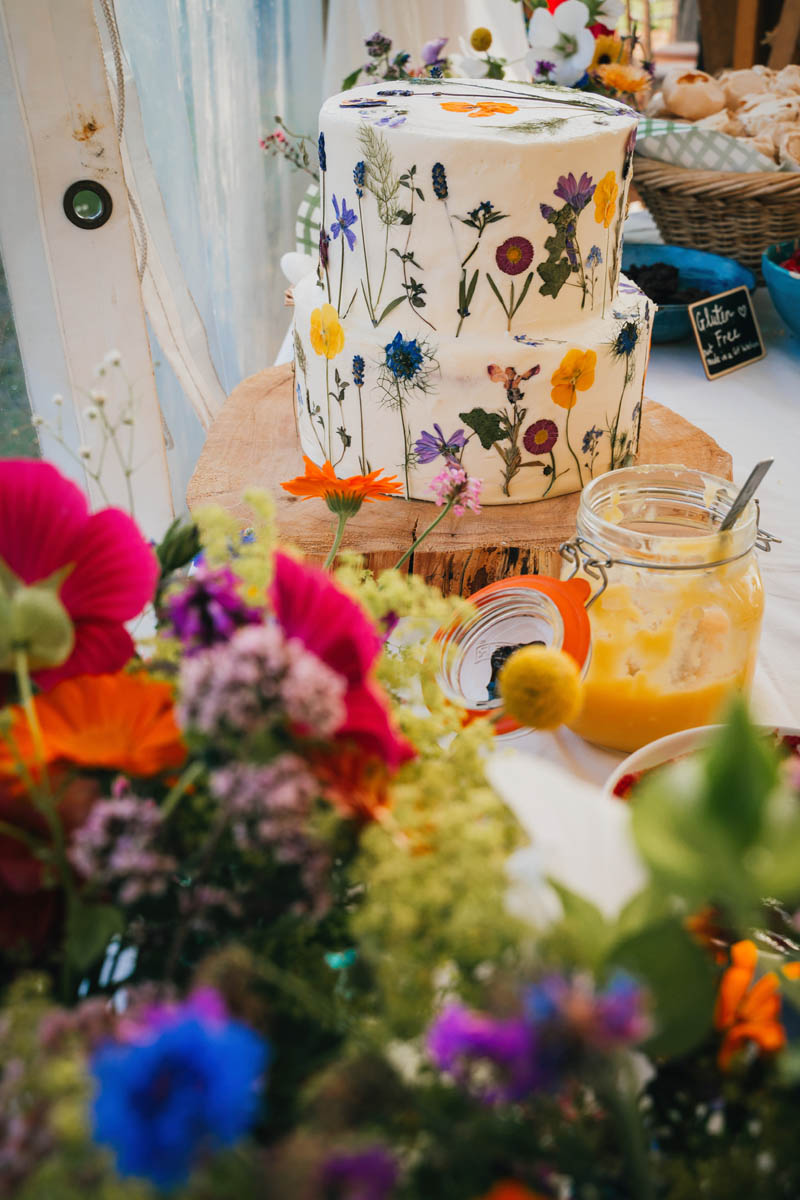 the wedding cake surrounded by brightly coloured bouquets