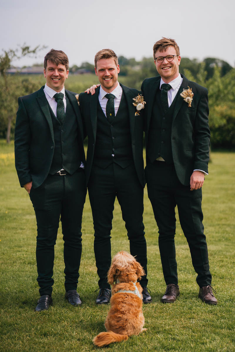 the groom and his best men with their ginger dog looking on