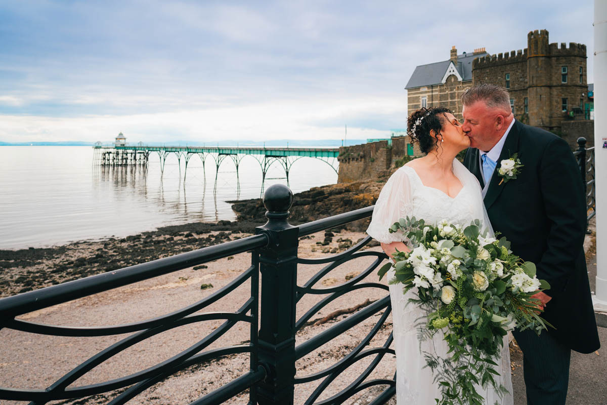 A couple kiss at the seaside with Clevedon Pier behind them