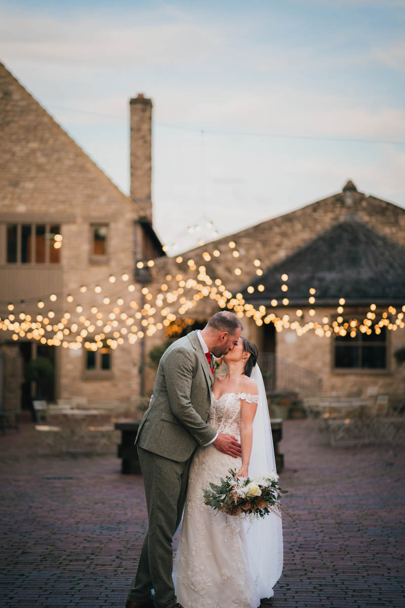 the groom dips his wife in a kiss in front of the wedding venue