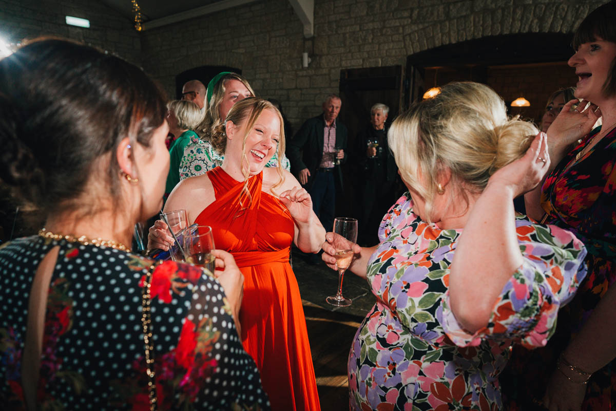 a bridesmaid dances with wedding guests who hold champagne glasses