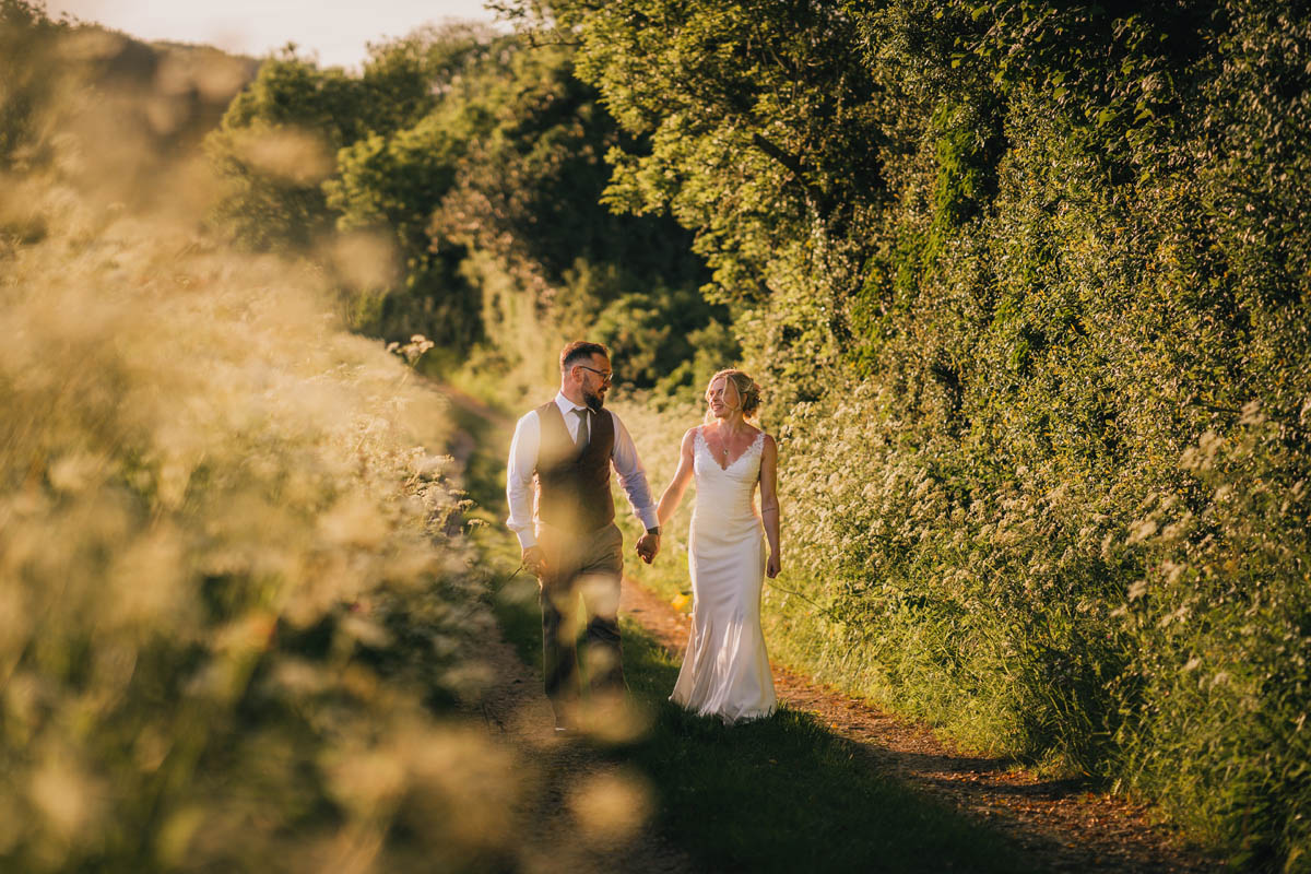 a woman and man walk hand in hand at sunset