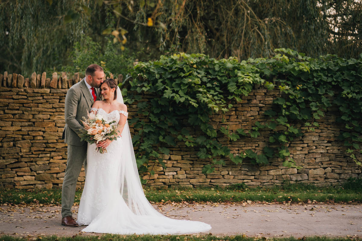 a groom kisses his wife as she holds the bouquet