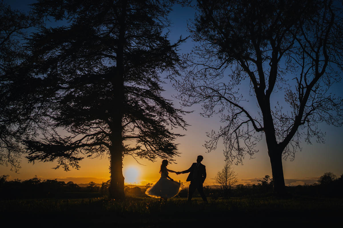 a silhouette of a woman and man dancing at dusk