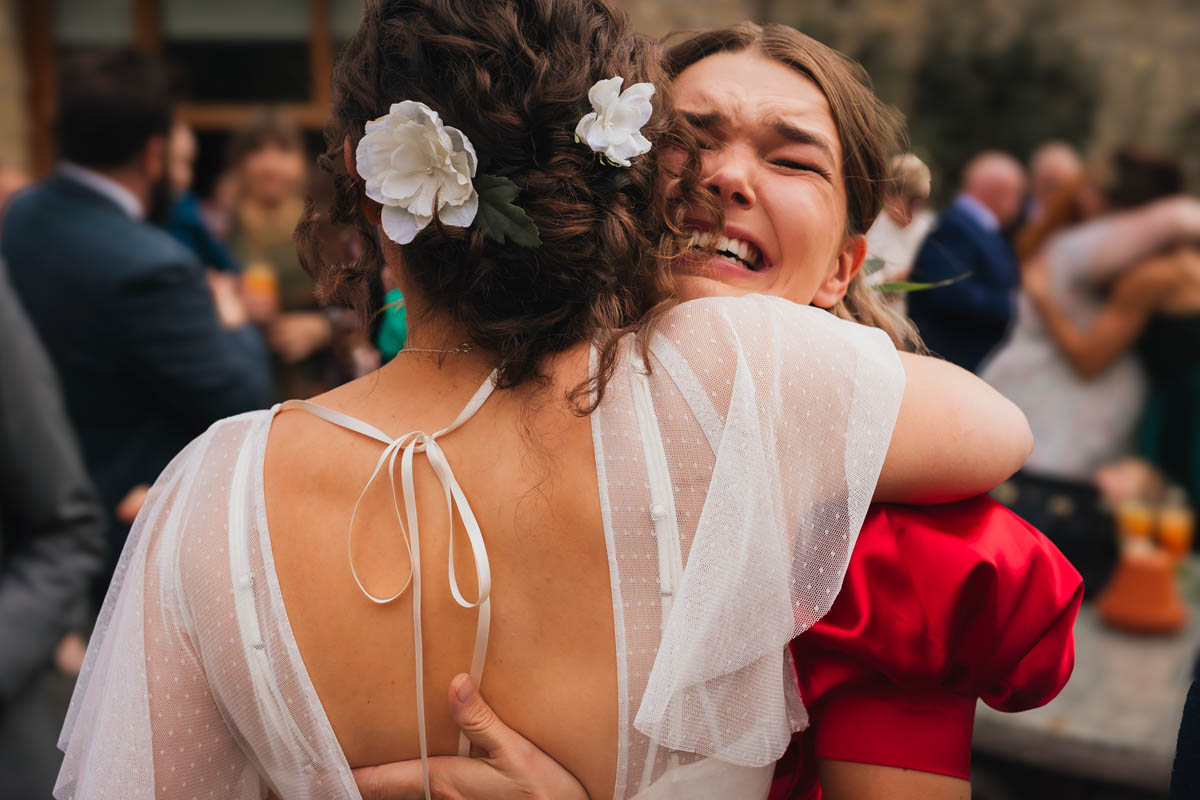 a woman hugs a bride and looks emotional