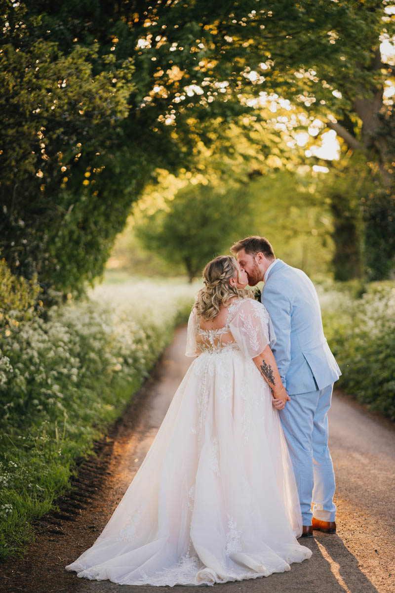 a couple kiss as they walk down a spring lane