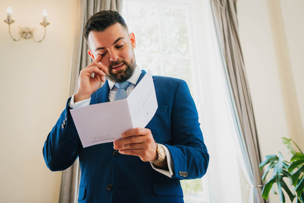 a man reads a card and wipes away a tear