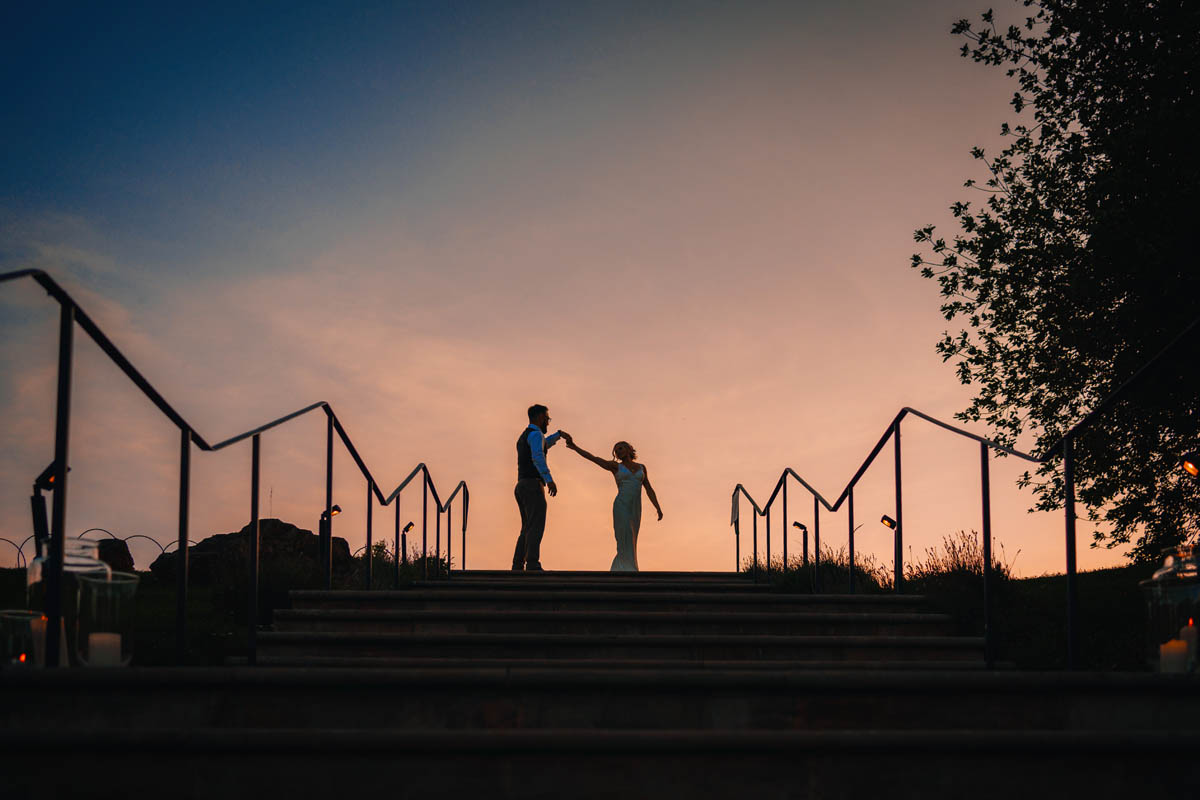 a silhouette of a couple dancing in the sky at dusk