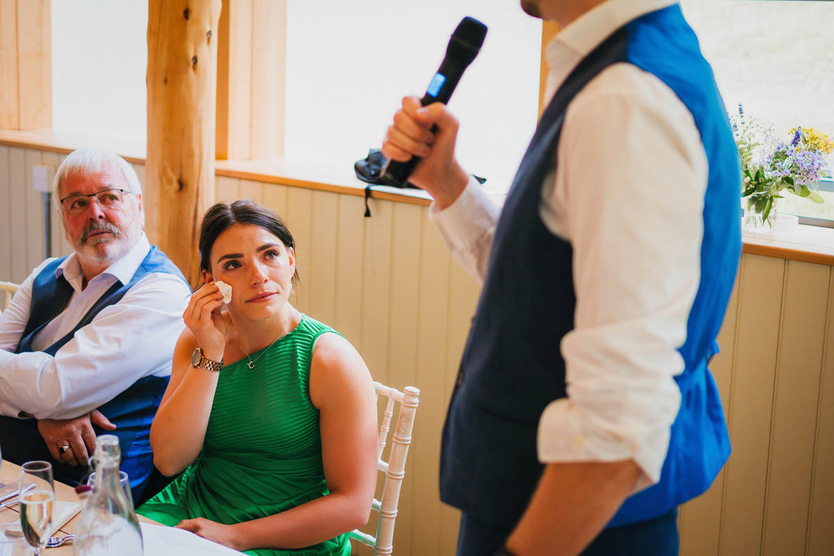 two people look emotional as someone delivers their speech