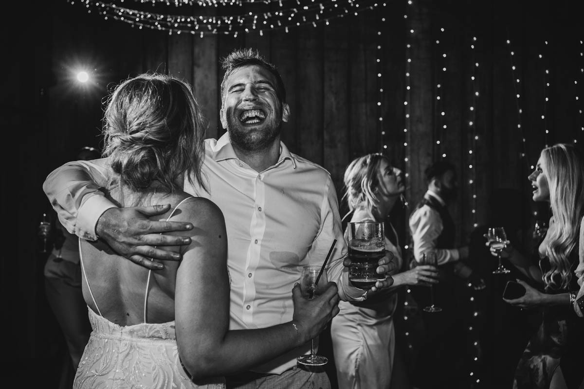 a man hugs his wife on the dancefloor as he smiles