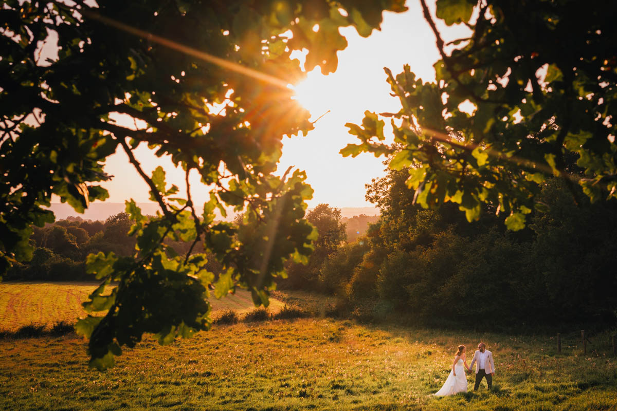 a couple walk through the herefordshire countryside in the wedding attire