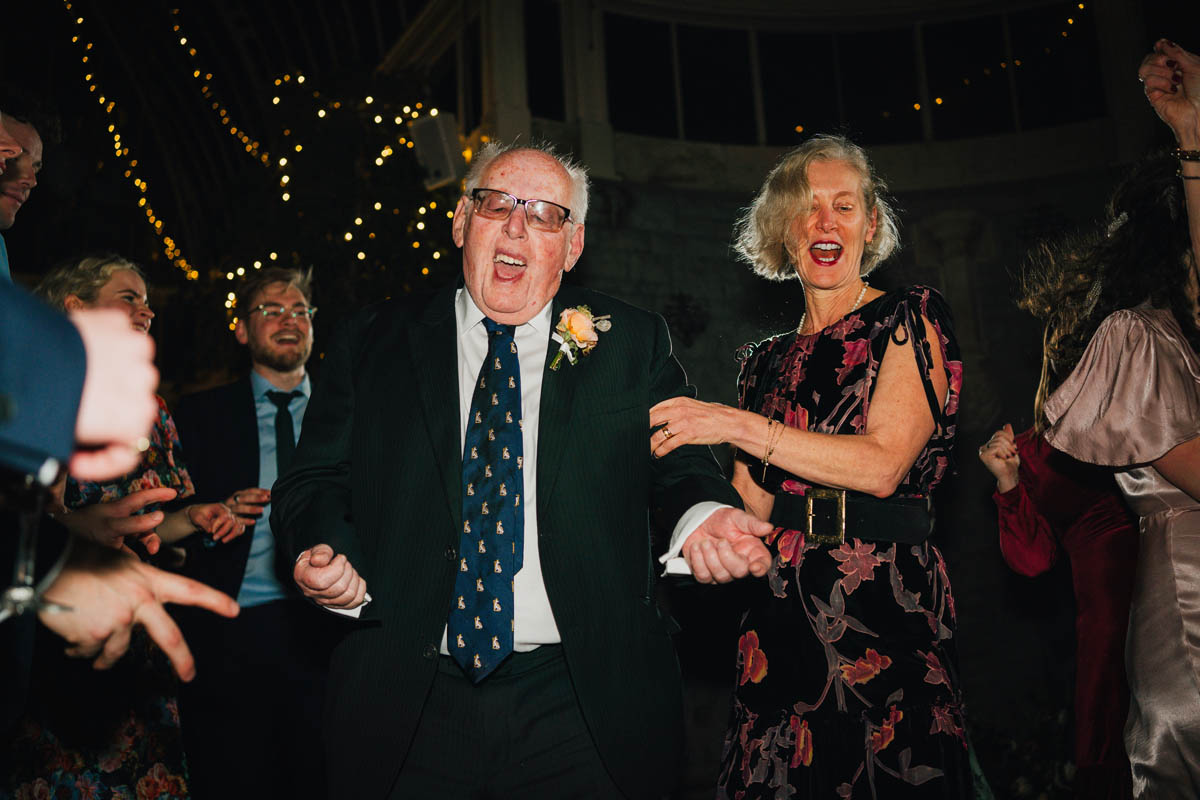 a woman holds onto an elderly man as he dances enthusiastically